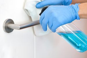 close up photo of gloved hands disinfecting a handle