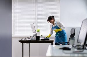 commercial cleaning service employee cleaning and disinfecting an office desk