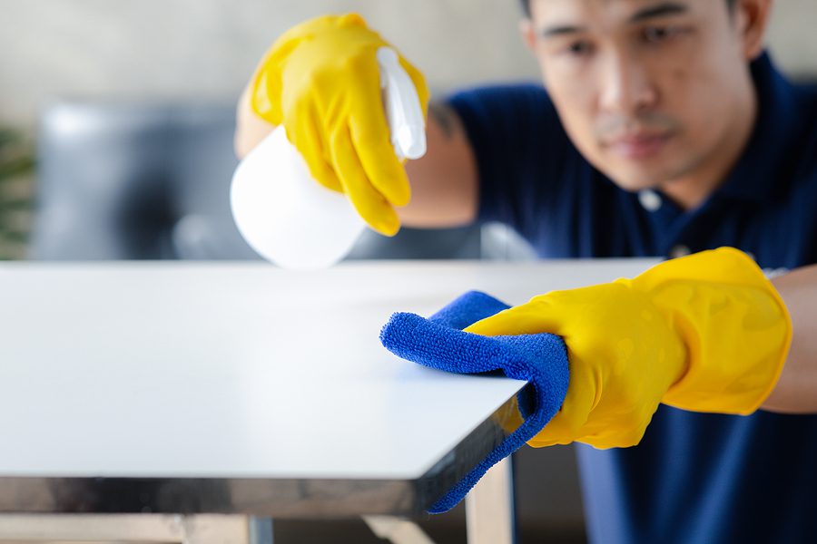 male professional cleaning service employee disinfecting a surface